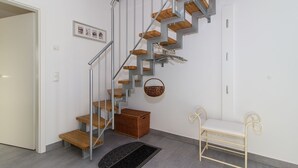 Een moderne trap met houten treden en metalen leuningen, een rieten mand en een bankje.