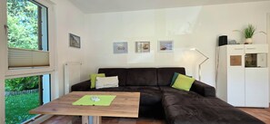 Een woonkamer met een bruine bank, een houten tafel en een wit kastje.