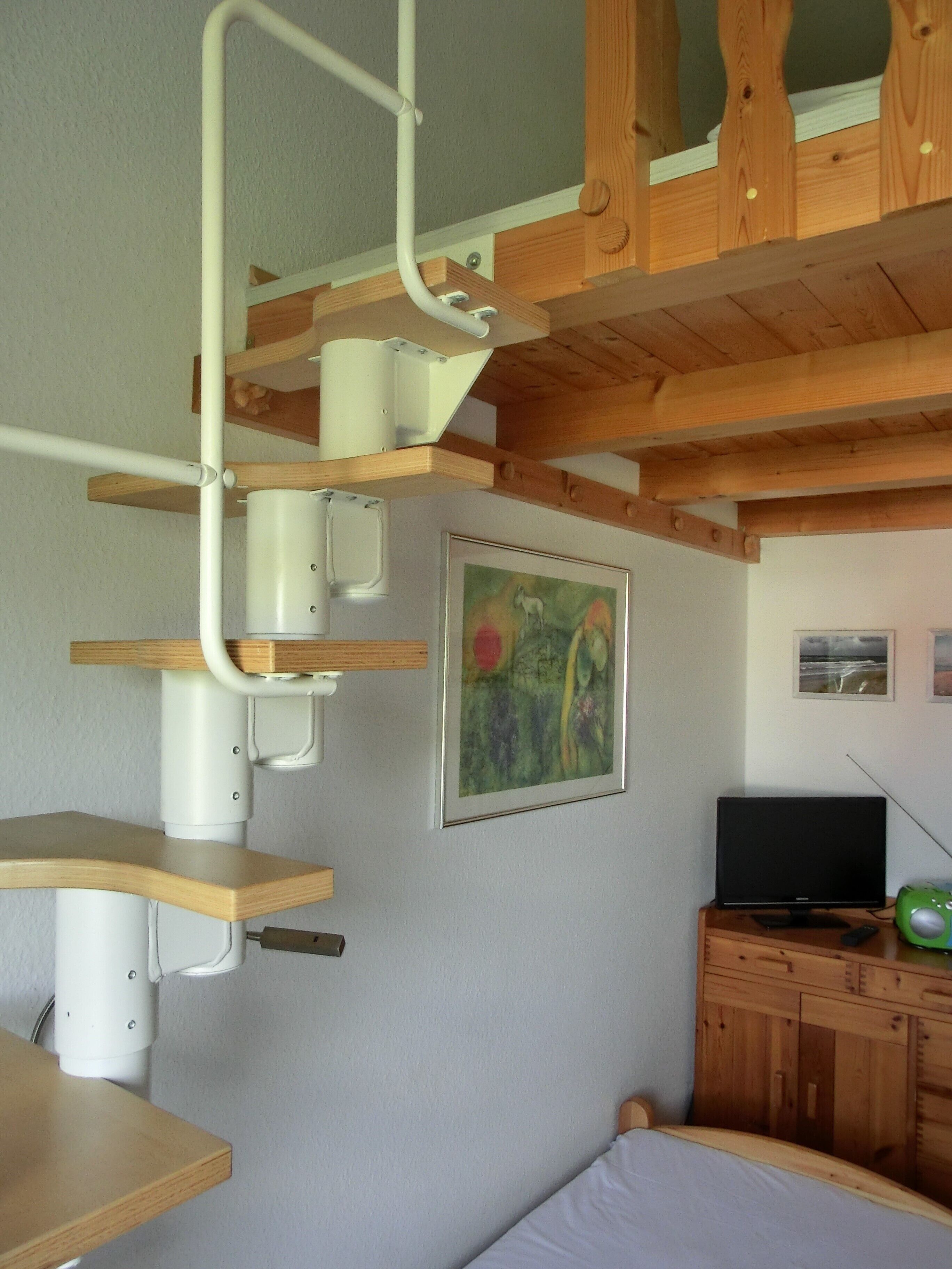 Una camera da letto con un letto a castello, travi in legno, una televisione e un altoparlante verde.
