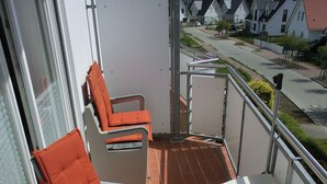 Een balkon met twee oranje fauteuils en een klein wit tafeltje.