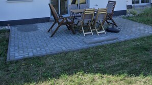 Una casa de dos pisos con un patio que tiene una mesa y sillas.