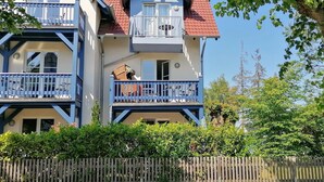 A two-story building with a red-tiled roof, blue balconies, and a wooden fence in front. - Sonnige Wohnung mit Süd-balkon und Strandkorb - M31 (Seeheilbad Graal-Müritz)