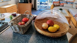 A kitchen area with wicker baskets containing apples and lemons, a coffee maker, and a wooden cabinet. - Sonnige Wohnung mit Süd-balkon und Strandkorb - M31 (Seeheilbad Graal-Müritz)