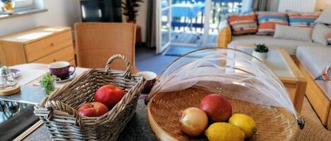 Una cocina con cestas de mimbre que contienen manzanas y limones, una cafetera y un mueble de madera.