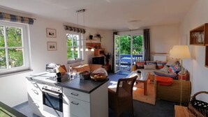 A modern kitchen with white cabinets, a built-in oven, and a dining area with a table and chairs. - Sonnige Wohnung mit Süd-balkon und Strandkorb - M31 (Seeheilbad Graal-Müritz)