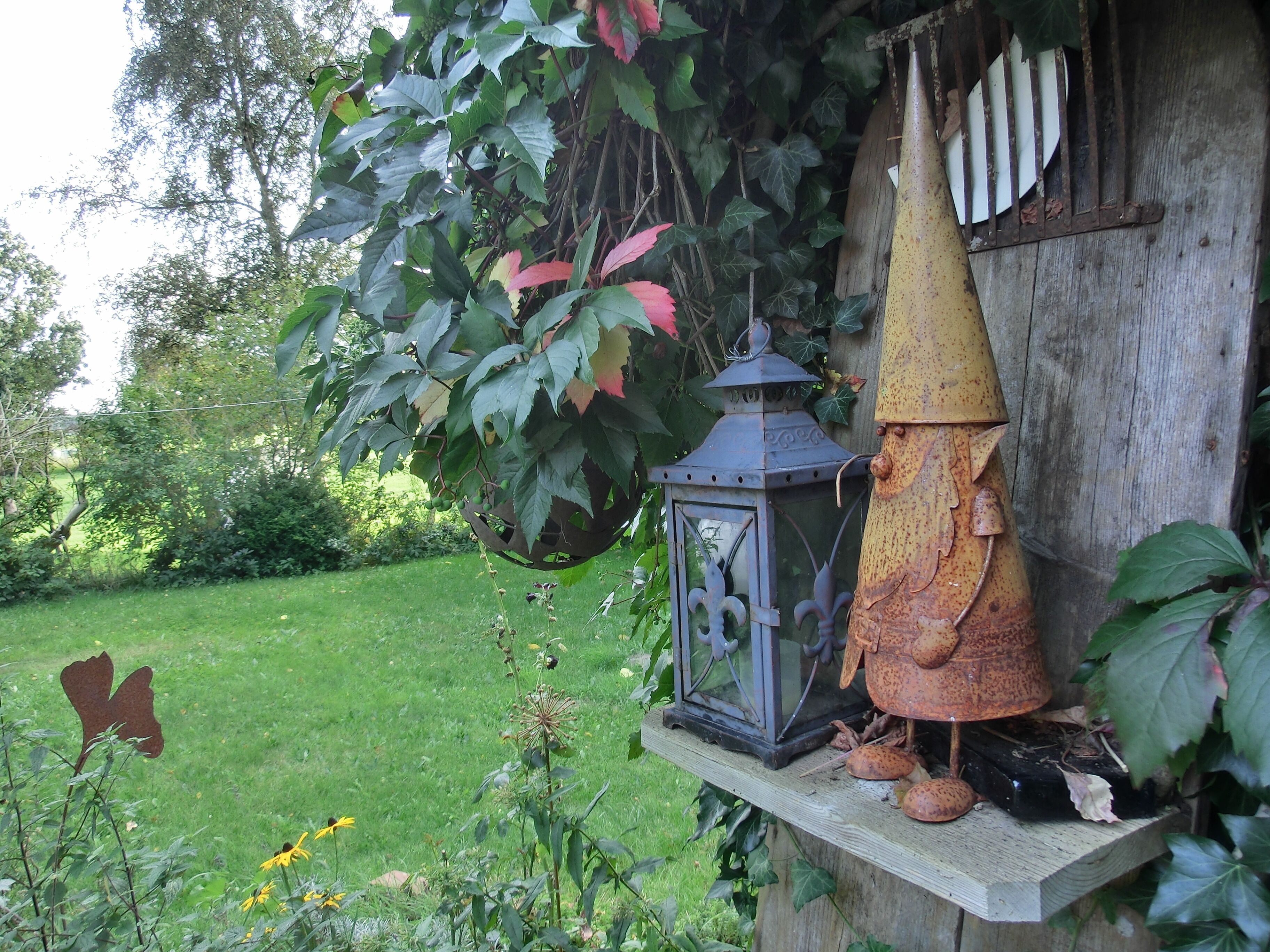 Een rustieke buitenomgeving met een houten constructie, een lantaarn en een vogelvoerder.