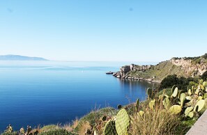 Un paysage côtier offrant une vue dégagée sur la mer, avec des falaises rocheuses et une végétation composée de cactus.
