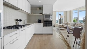 A modern kitchen with white cabinets, a built-in oven, and a microwave. - Stylish Corner Unit. Views & Comfort. Feel at Home (Calgary)