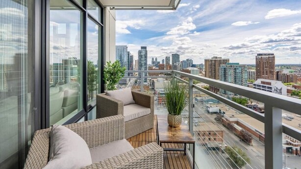 A balcony with wicker furniture and a view of a cityscape. - Stylish Corner Unit. Views & Comfort. Feel at Home (Calgary)