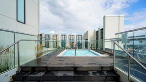 A rooftop pool with glass railings, a clear sky, and a cityscape view. - Stylish Corner Unit. Views & Comfort. Feel at Home (Calgary)