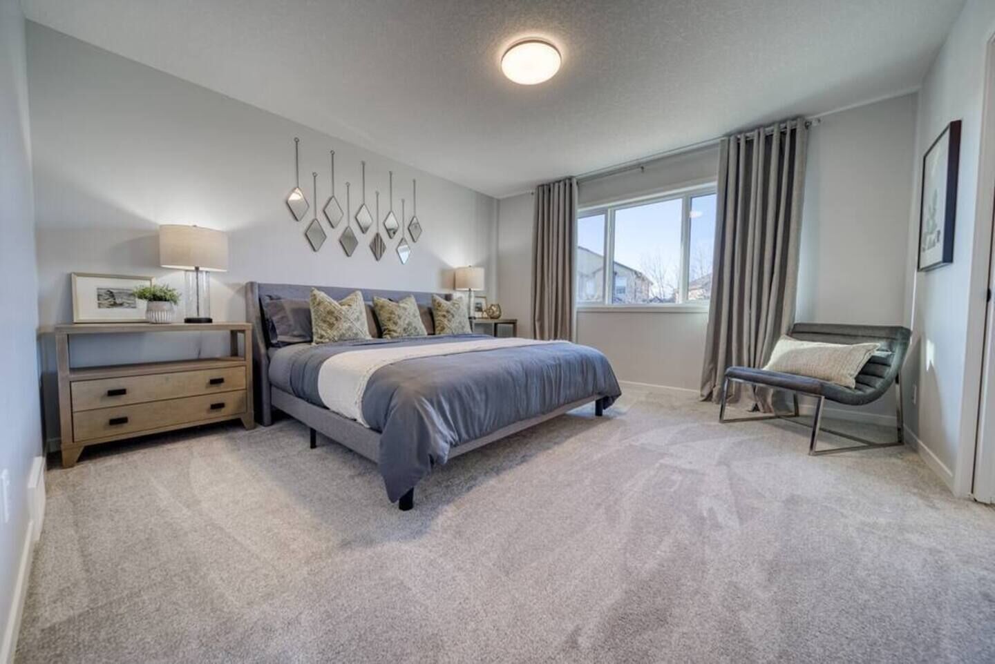 A bedroom with a bed, bedside tables, a chair, and a window with curtains.