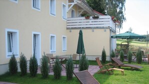 A hotel patio with lounge chairs, a table, and umbrellas. - Holiday apartment Gohrisch, Landhaus Böhmer***** (Papstdorf)