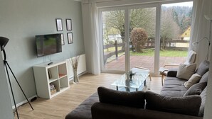 A modern living room with a sofa, a coffee table, a TV, and a bookshelf. - Holiday apartment Gohrisch, Landhaus Böhmer***** (Papstdorf)