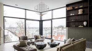 Una sala de estar moderna con ventanas amplias, un candelabro y una estantería.