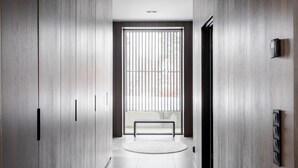 Un pasillo con paneles de madera, un banco y una puerta que da a una habitación.