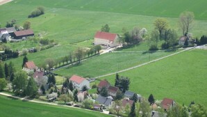 A rural landscape with a large white building surrounded by smaller houses, fields, and a road. - FeWo Zirkelstein, Landhaus Böhmer***** (Papstdorf)