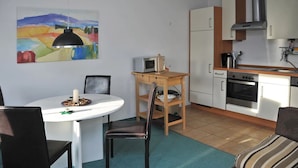 A compact kitchen with a microwave, oven, and a painting above the counter. - Apartment Papststein, Landhaus Böhmer***** (Papstdorf)