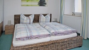 A double bed with a striped bedspread, a wicker headboard, and a bedside table with a lamp. - Apartment Papststein, Landhaus Böhmer***** (Papstdorf)