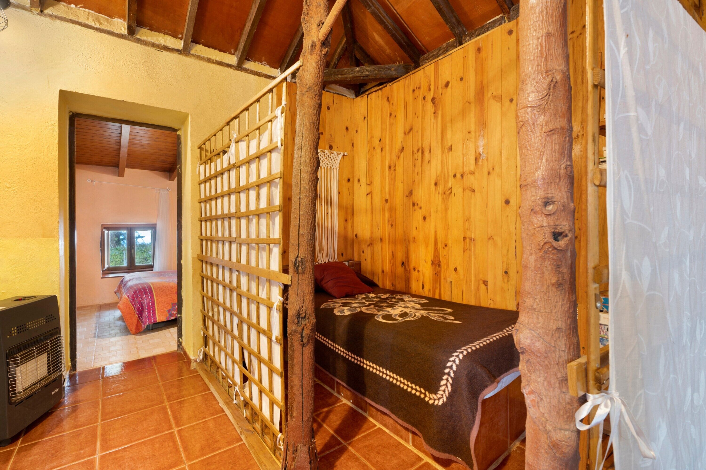 Habitació de fusta amb llit, un calefactor i una finestra.