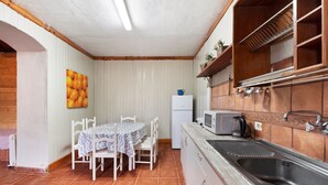 A compact kitchen with white cabinetry, a built-in microwave, and a stainless steel sink.