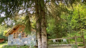 Un rustico chalet con pareti in pietra e un terrazza in legno.