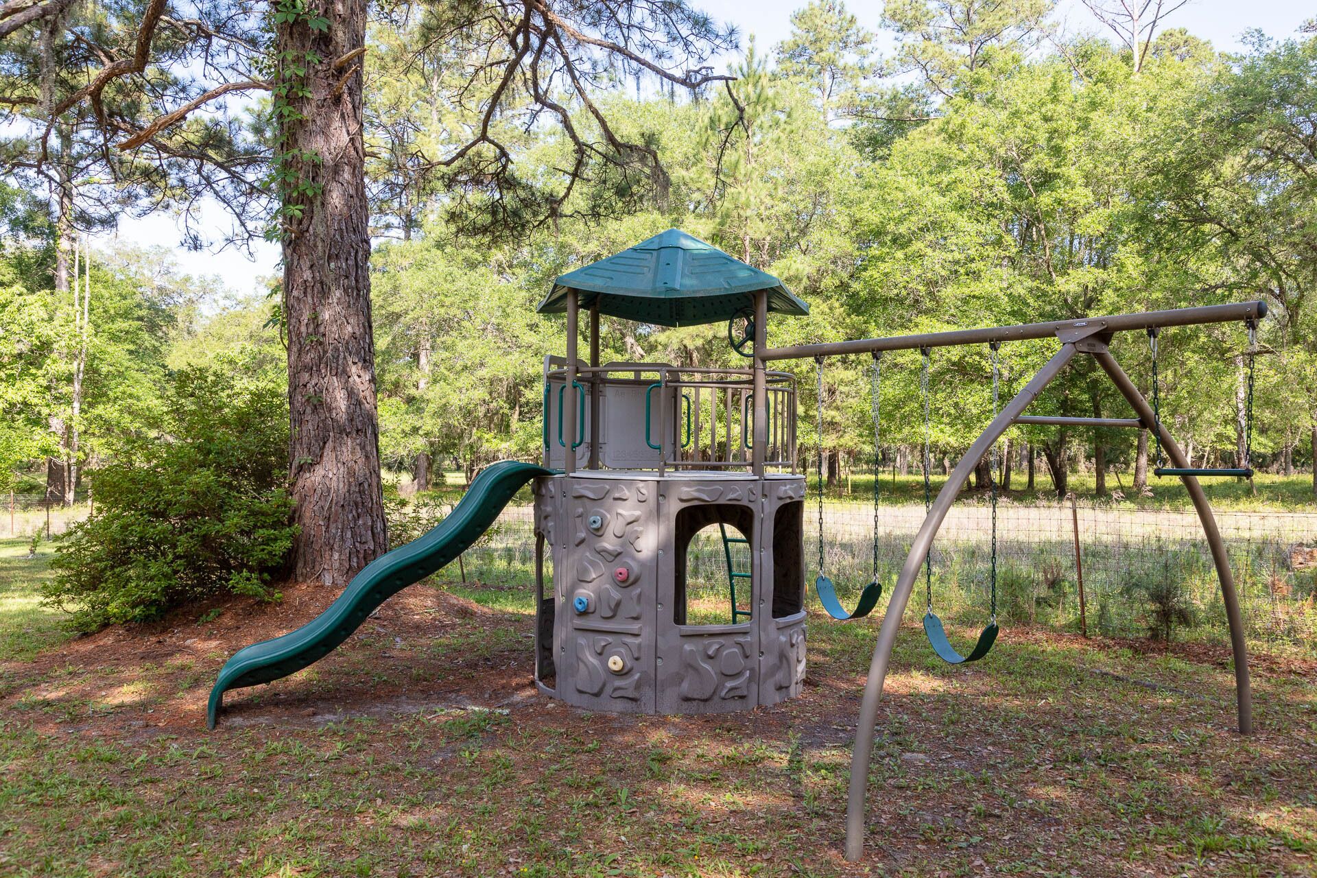 Children's swings, slides and playhouse in the back yard by the rear door and garage. (1)