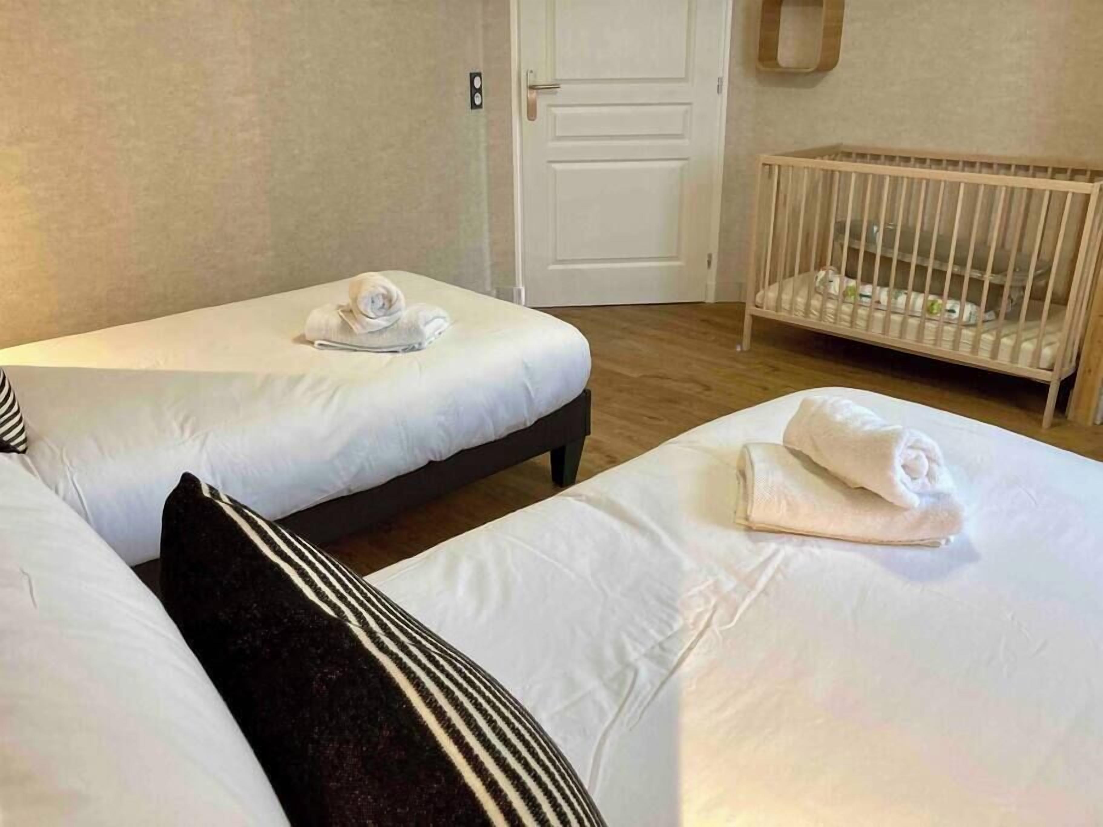 Een hotelkamer met twee eenpersoonsbedden, een ledikant en een deur.