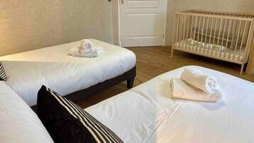 Een hotelkamer met twee eenpersoonsbedden, een ledikant en een deur.