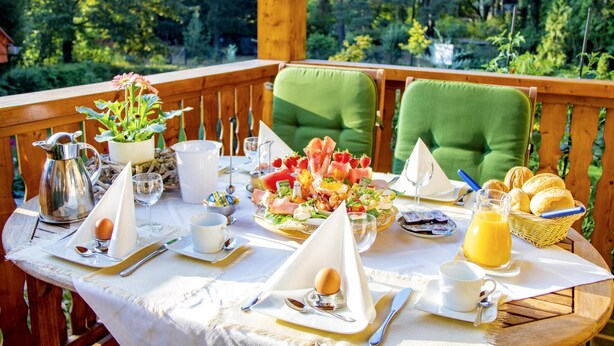 Mesa para el desayuno al aire libre con diversos alimentos, como frutas, pasteles y bebidas.