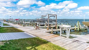 A wooden pier with boats docked, a table, and chairs.
