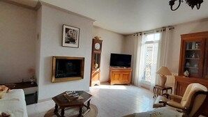 A living room with a sofa, a coffee table, a television, a clock, and a cabinet. - La Vigneronne de Mamie (Puimisson)