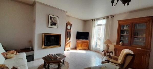 Un salon comprenant un canapé, une table basse, un téléviseur, une horloge et un meuble.