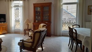 A living room with a television, wooden furniture, a dining table, and a view of the outside. - La Vigneronne de Mamie (Puimisson)