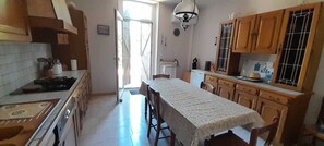 Une cuisine avec des meubles en bois, un pare-feu en carrelage et un coin repas comprenant une table et des chaises.