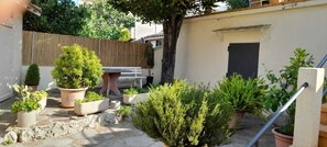 Un petit jardin avec des plantes en pot, une clôture en bois et une porte.