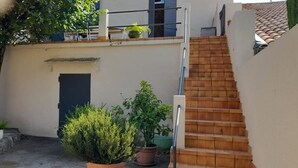 A staircase leading up to a building with a door and potted plants. - La Vigneronne de Mamie (Puimisson)
