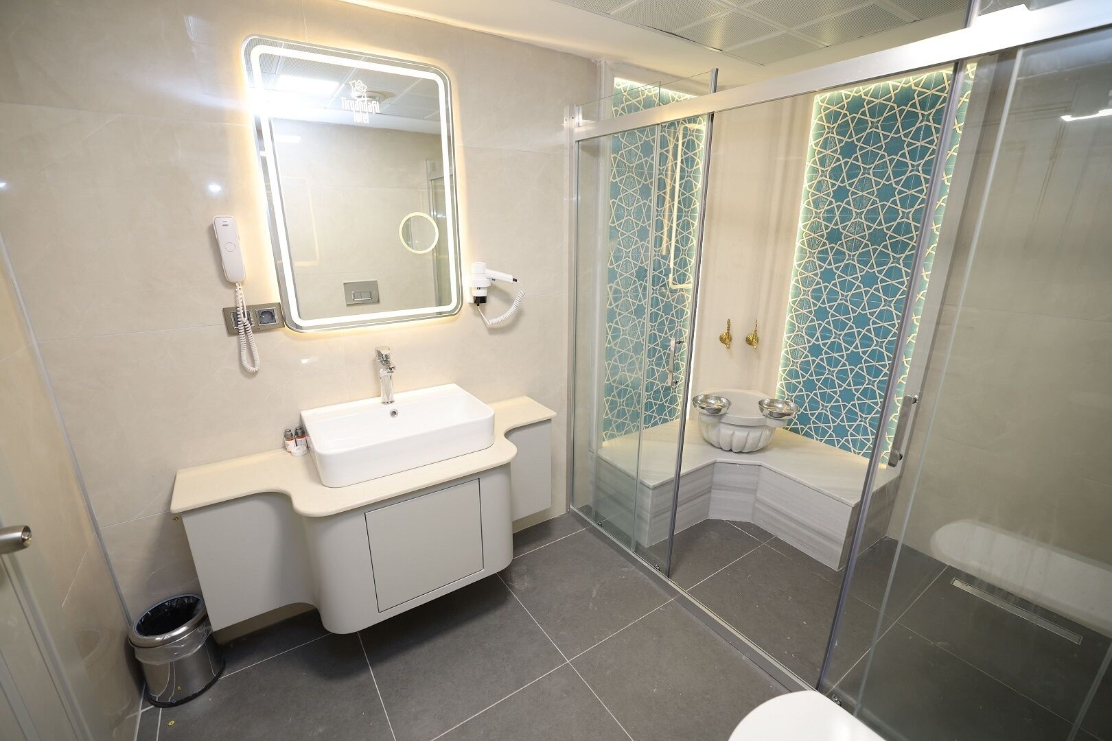 Un baño moderno con un lavabo blanco, un espejo y una cabina de ducha de vidrio.