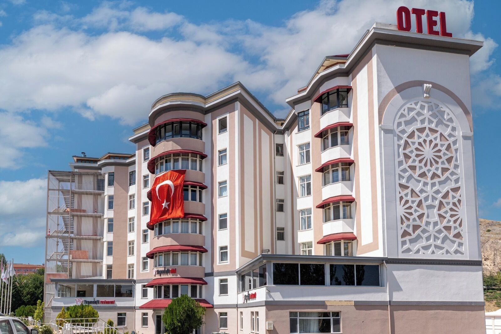 Un hotel de varios pisos con un llamativo letrero rojo y blanco, balcones y una fachada decorativa.