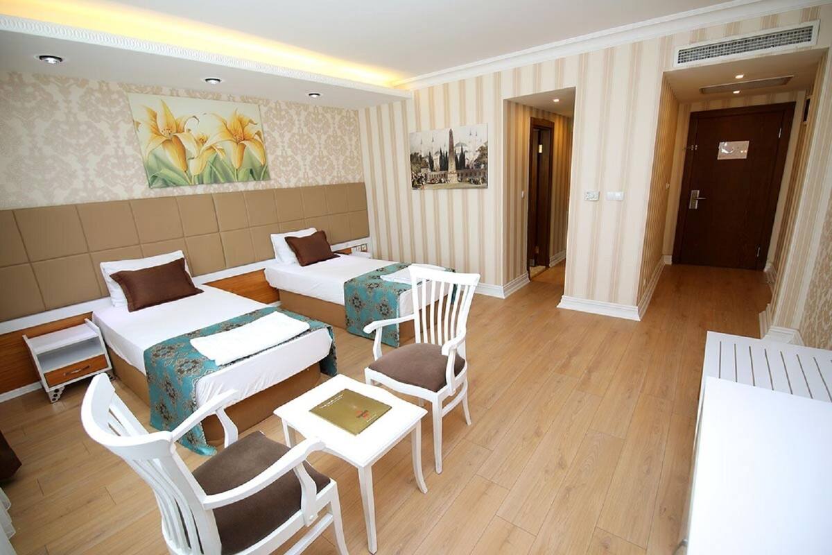 A hotel room with two beds, a small table, and two chairs.