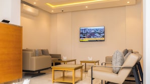 Un salon moderne comprenant un canapé, des fauteuils, une table basse et un téléviseur à écran plat fixé au mur.