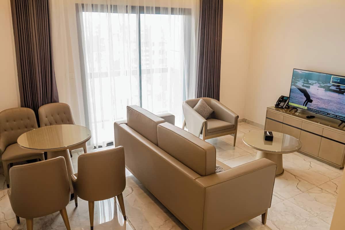 A modern living room with a sofa, chairs, a coffee table, and a television on a stand.