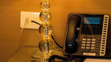 Een glazen tafel met een lamp, telefoon en notitieboekje.