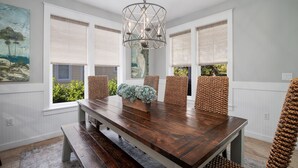 Un espace repas comprenant une table en bois, des chaises en osier et un luminaire suspendu.