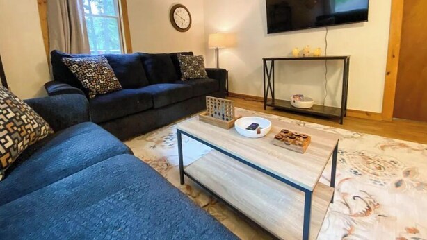 A living room with a sofa, a coffee table, a TV, and a lamp. - Spacious 4 BR with theater, close to Airport (Fairbanks)