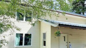 A single-story house with a covered porch, a front door, and a small garden area. - Spacious 4 BR with theater, close to Airport (Fairbanks)