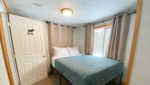 Ein Schlafzimmer mit Bett, Tür und einem Vorhangfenster.