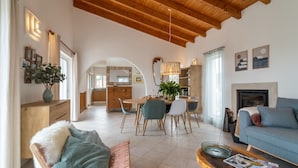 Un'ampia zona giorno con soffitto in legno, un tavolo da pranzo con sedie, un divano e un camino.