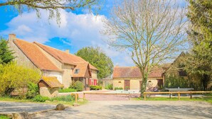 A rustic village with traditional stone buildings, a paved courtyard, and a wooden fence.