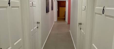Un couloir avec des portes blanches numérotées 3, 4, 6 et 7.