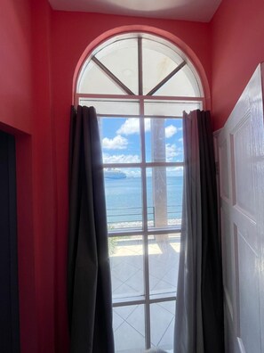 Una stanza con un'ampia finestra ad arco, una porta e vista sul mare.